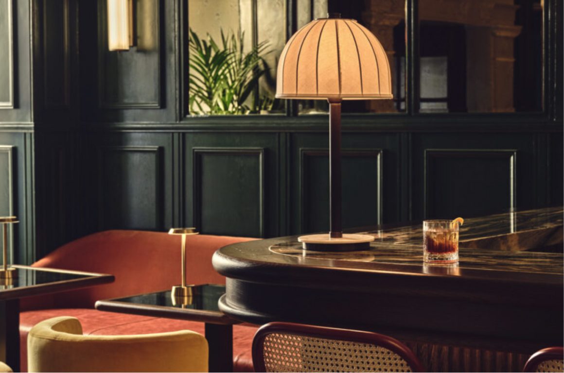 Dark-panelled hotel bar with a domed table lamp